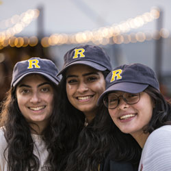 Three University of Rochester sophomores posed together while wearing University of Rochester hats. 